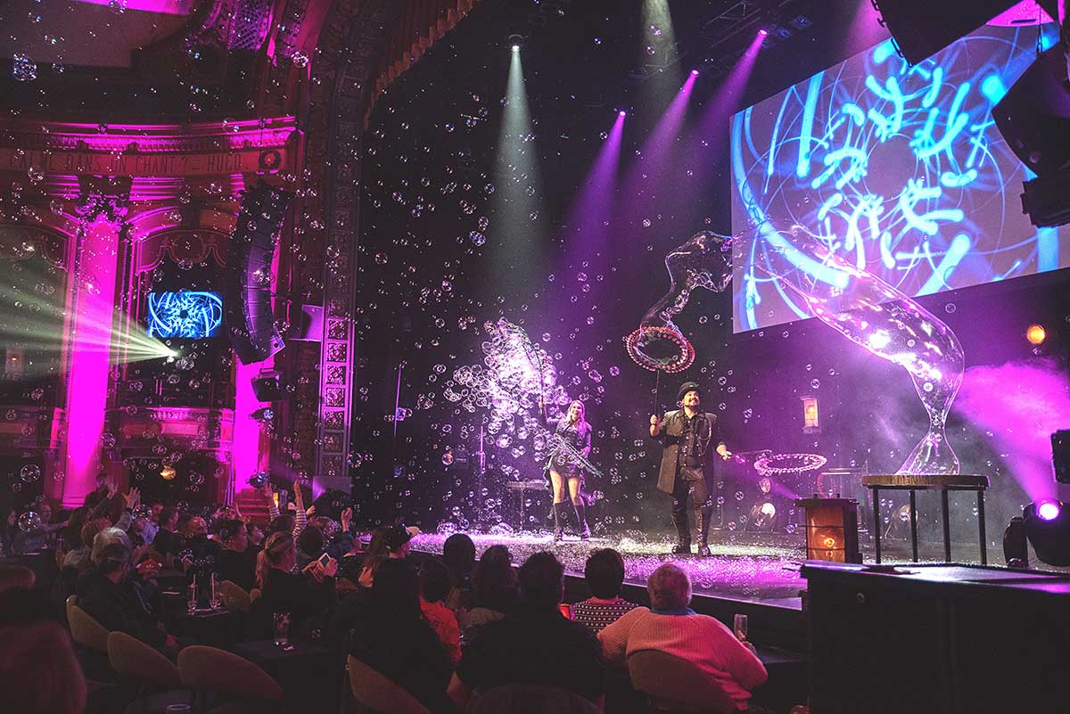 Scena dello spettacolo Bubbles Revolution al Teatro Alfieri: i due artisti creano bolle di sapone illuminate da luci colorate, con effetti visivi